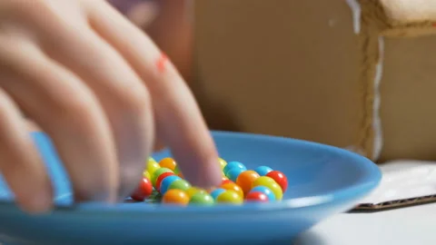 Cute child decorating gingerbread cookie house, closeup colorful festive candies Vidéo 122561956
