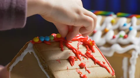 Cute child decorating gingerbread cookie house with festive candies Stock Footage 122565953