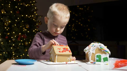 Cute child decorating gingerbread cookie house with festive candies Stock Footage 122568433