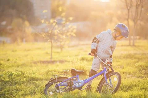 Cute child is driving a bike on a sunny day at sunset Stock Photos
