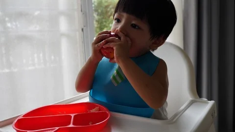 Cute child enjoy eating bite a apple in home Stock Footage 93886989