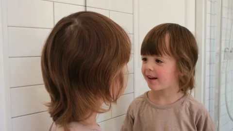 Cute child examines himself in mirror Stock Footage 156029356