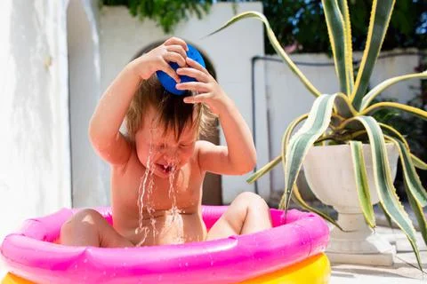 Cute child has fun in inflatable pool with toys in summer in backyard. 写真素材