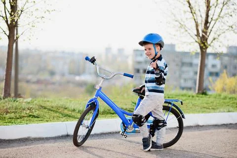 Cute child in helmet and protection stands near his bike Stock Photos