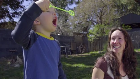 Cute child keeps trying to blow bubble until he succeeds Stock Footage 74118276