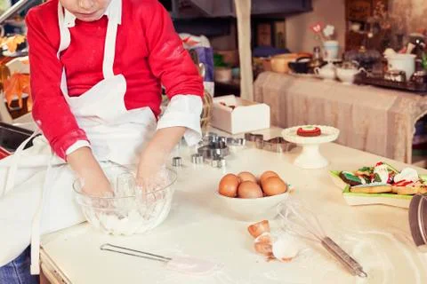 Cute child in the kitchen while mixing the dough Stock Photos