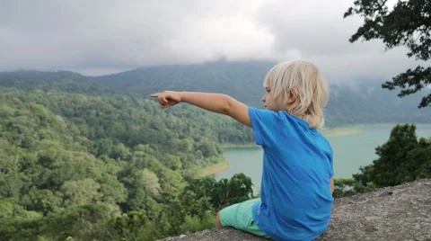 Cute child looking into the distance sitting on a high bluff Video stock 68030372