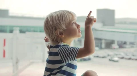 Cute child looking out the window in airport and pointing at plane taking off Vidéo 65886282