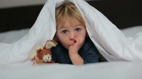 Cute child, lying in bed, playing with little stuff toy, smiling happily Video stock 147374919