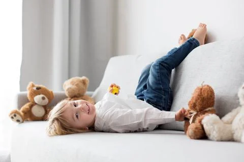 Cute child, lying in bed, reading book Stock Photos