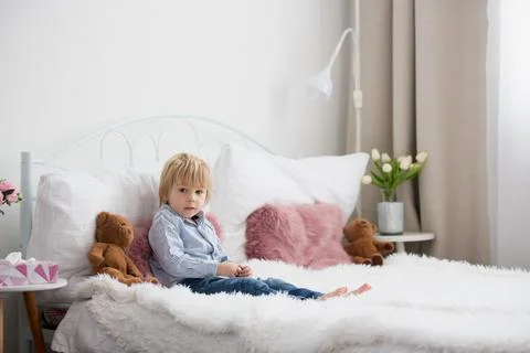 Cute child, lying in bed, reading book Stock Photos