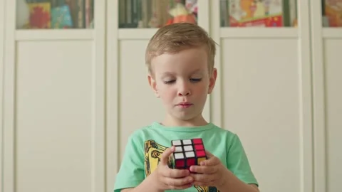 Cute child playing with a Rubiks cube. Ssmart boy solving a logic puzzle Stock Footage 335504562