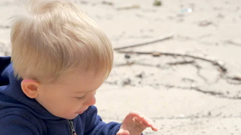 A cute child   is playing with sand on a beach Vídeos de archivo 107109952