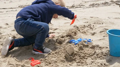 A cute child   is playing with sand on a beach 스톡 동영상 107113987
