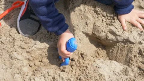 A cute child   is playing with sand on a beach Vídeos de archivo 107114432