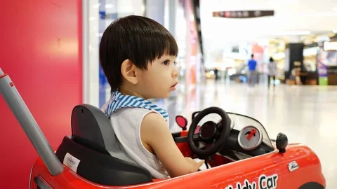 Cute child playing small car toy in shopping mall department store Stock Footage 94171335