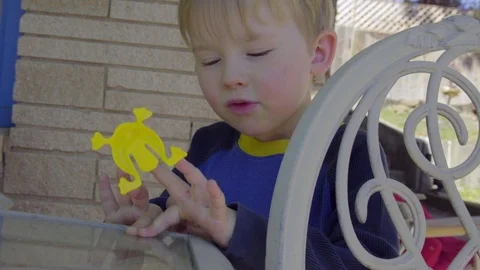 Cute child plays with toy on table in backyard Stock Footage 75056624