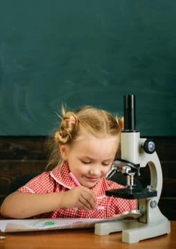 Cute child research with microscope optical instrument at school classroom Stock Photos
