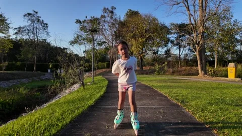 Cute child roller skating in the park and looking at camera. Stockbeeldmateriaal 265011555