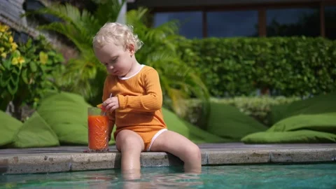 A cute child is sitting by the pool drinking a healthy tropical fruit smoothie Video stock 171786754