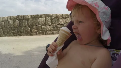 Cute child sitting on stroller and eating ice cream. Happy kid eating ice cream Stock Footage 107597197