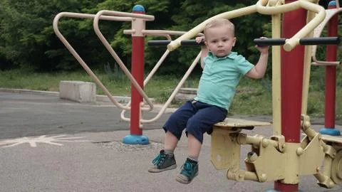 Cute child sitting on the training apparatus in a sportground 스톡 사진