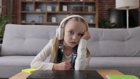 Cute child studying remotely at home using laptop. Tired primary schoolgirl Stock Footage 201267982