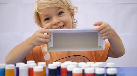 Cute child taking out of the box colorful paint. Showing empty box Stock Footage 50265706
