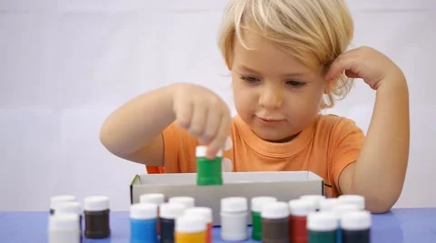 Cute child taking out of the box colorful paint. Showing empty box and smiling Stock Footage 50265829