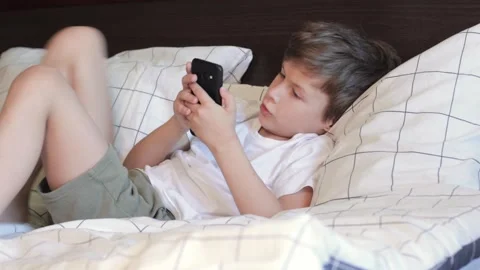 Cute child talking by video call on smartphone while lying in bed Stock Footage 160374302