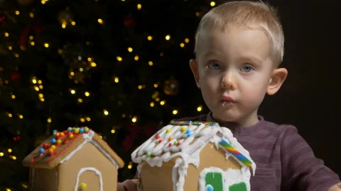 Cute child trying to eat, bite decorated gingerbread cookie house Stockbeeldmateriaal 122572719