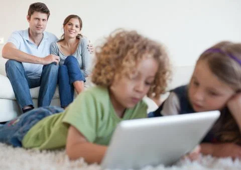 Cute children using a tablet computer while their happy parents are watching Stockfoto's