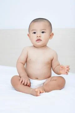 Cute Chinese baby boy sitting in bed Stock Photos