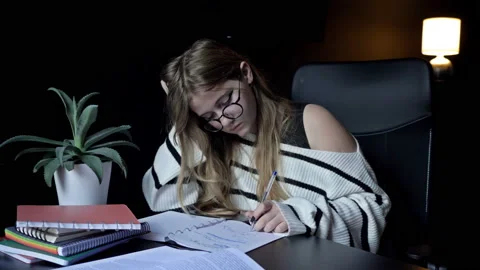 Cute college student stayed up late doing her homework. Tired girl wants to Stock Footage 235718302