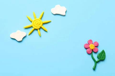 Cute composition with flower, sun and clouds made of plasticine on blue backg Stock Photos