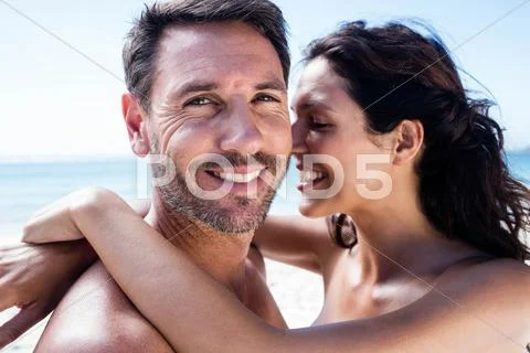 Cute Couple Cuddling With Arms Around On The Beach