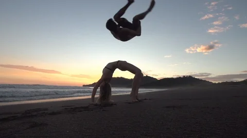 Cute Couple do Back Bend and Flip on Sunset Beach Stock Footage 87723628