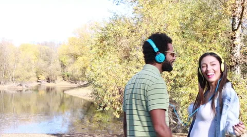 Cute couple with headphones listening to music and dancing by the lake Stock Footage 59555698