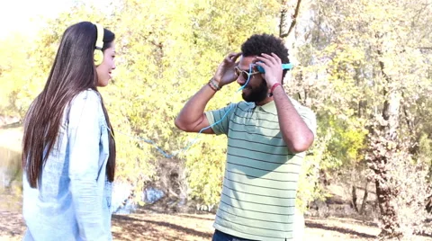 Cute couple with headphones listening to music and dancing by the lake Stock Footage 59555716