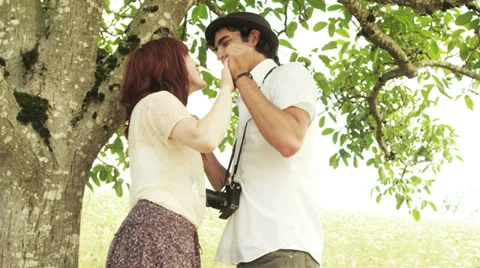 Cute couple hold hands under a tree and look at each other Stock Footage 33869436