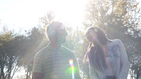 Cute couple listening to music with headphones on sunny day Stock Footage 59555511
