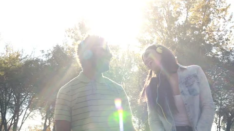 Cute couple listening to music with headphones on sunny day Stock Footage 59555517