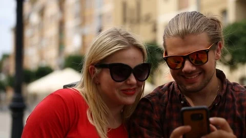 Cute couple looking on smartphone in the cafe and smiling to the camera Stock Footage 77476959