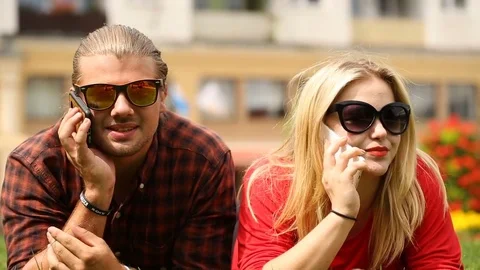 Cute couple lying on the grass and chatting on cellphones Stock Footage 77483700