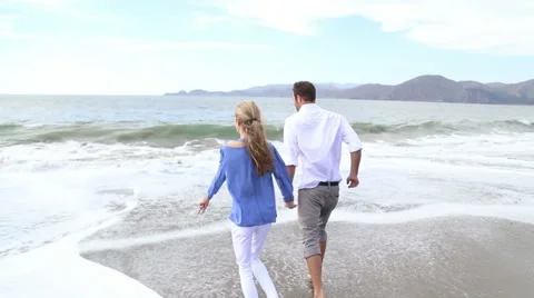Cute couple running away from the waves at Baker Beach San Fransisco Stock Footage 41969087