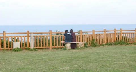 Cute couple sited on a bench looking at the sea at Cape chinen Okinawa, Japan. Stock Footage 122886457