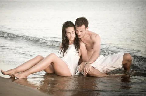 Cute couple sitting in shallow water together. Stock Photos