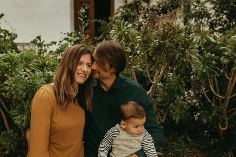 Cute couple standing together while man holds their baby son Stock Photos