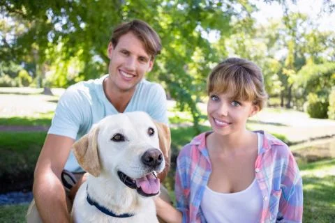 Cute couple with their labrador dog in the park Stock Photos