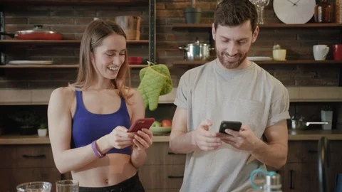 Cute couple using smartphone together at home in the kitchen, sharing posts Stock Footage 111963984